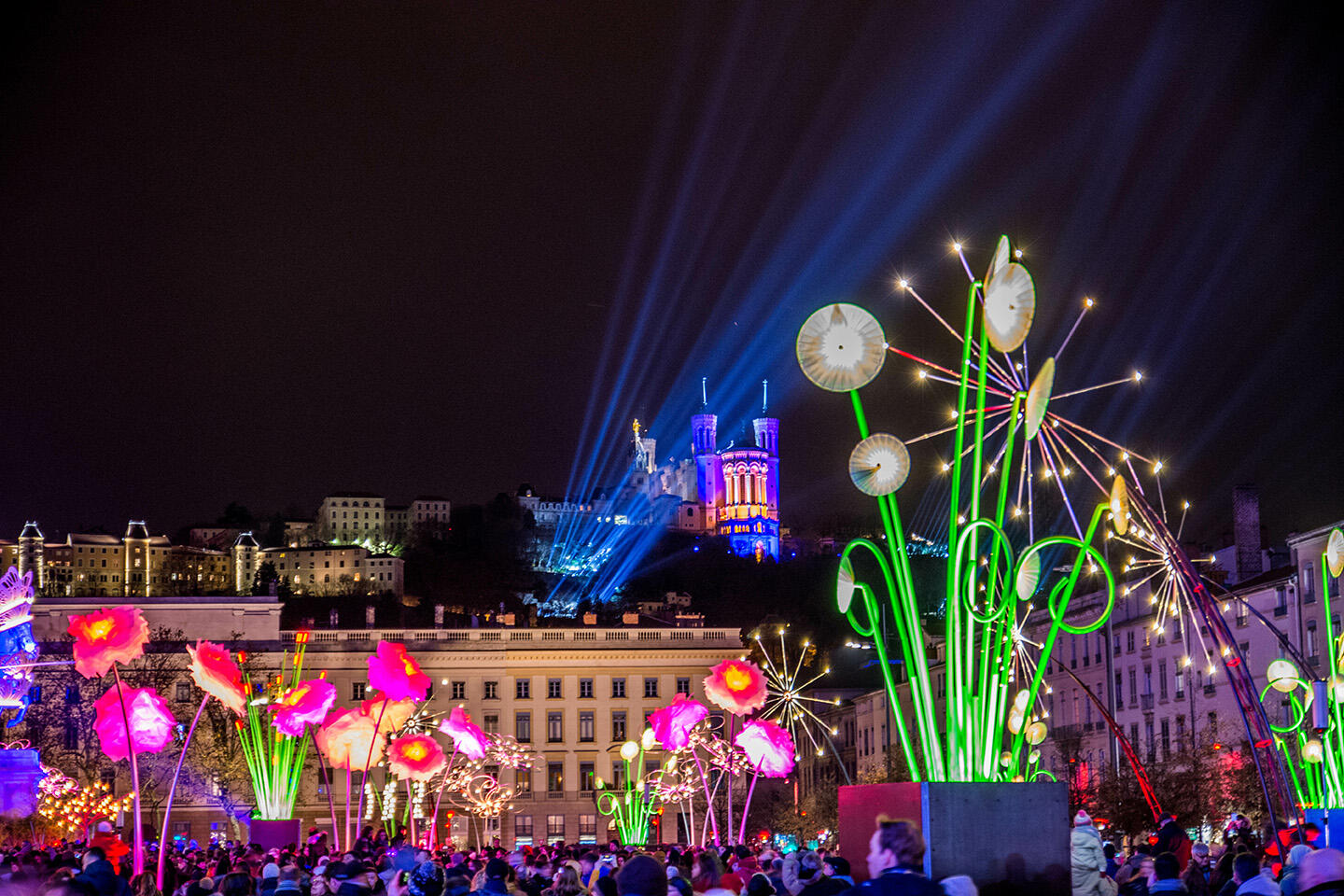 Vista del Festival de Luces en Lyon con la basílica iluminada e instalaciones florales coloridas, alojamiento en Appart’City.