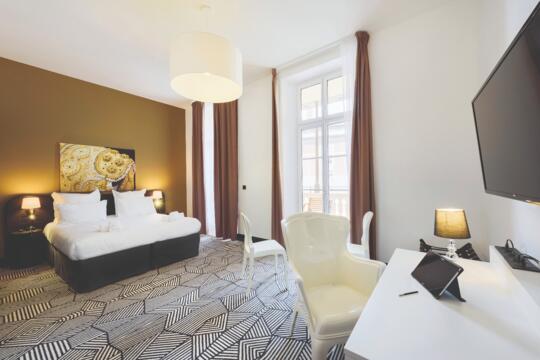 Chambre d'appart'hôtel Appart'City élégante avec lit double, décoration contemporaine et espace bureau, alliant confort et fonctionnalité pour les voyageurs modernes.