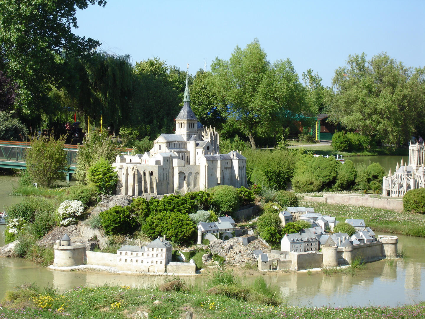 Maqueta detallada de un castillo francés rodeado de edificios históricos en miniatura y vegetación, reflejando la herencia de Francia en el parque France Miniature.