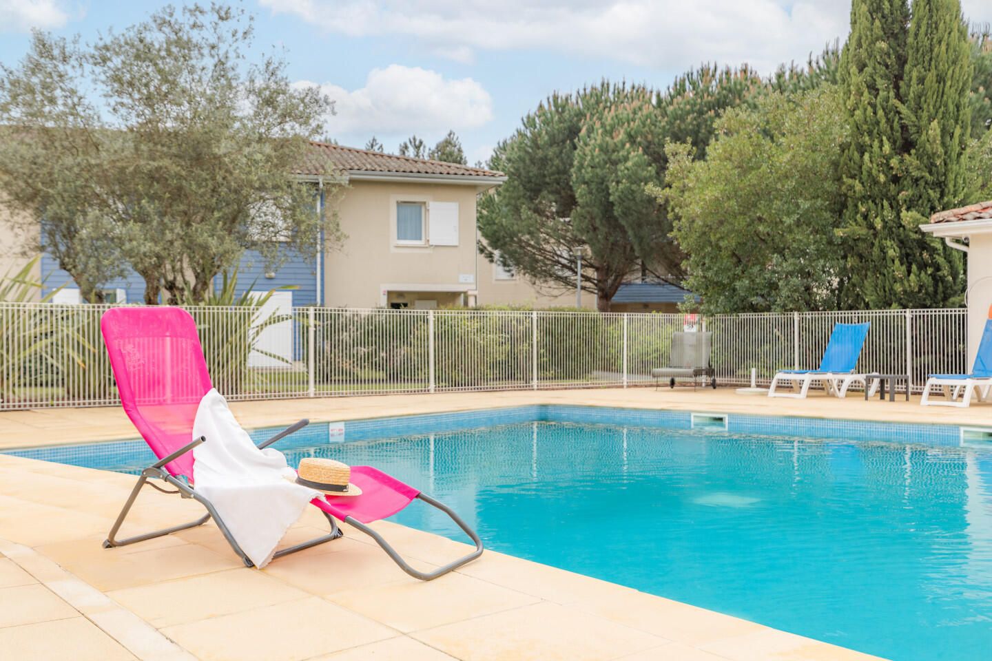 Aussenpool von Appart’City mit einem bequemen rosa Liegestuhl