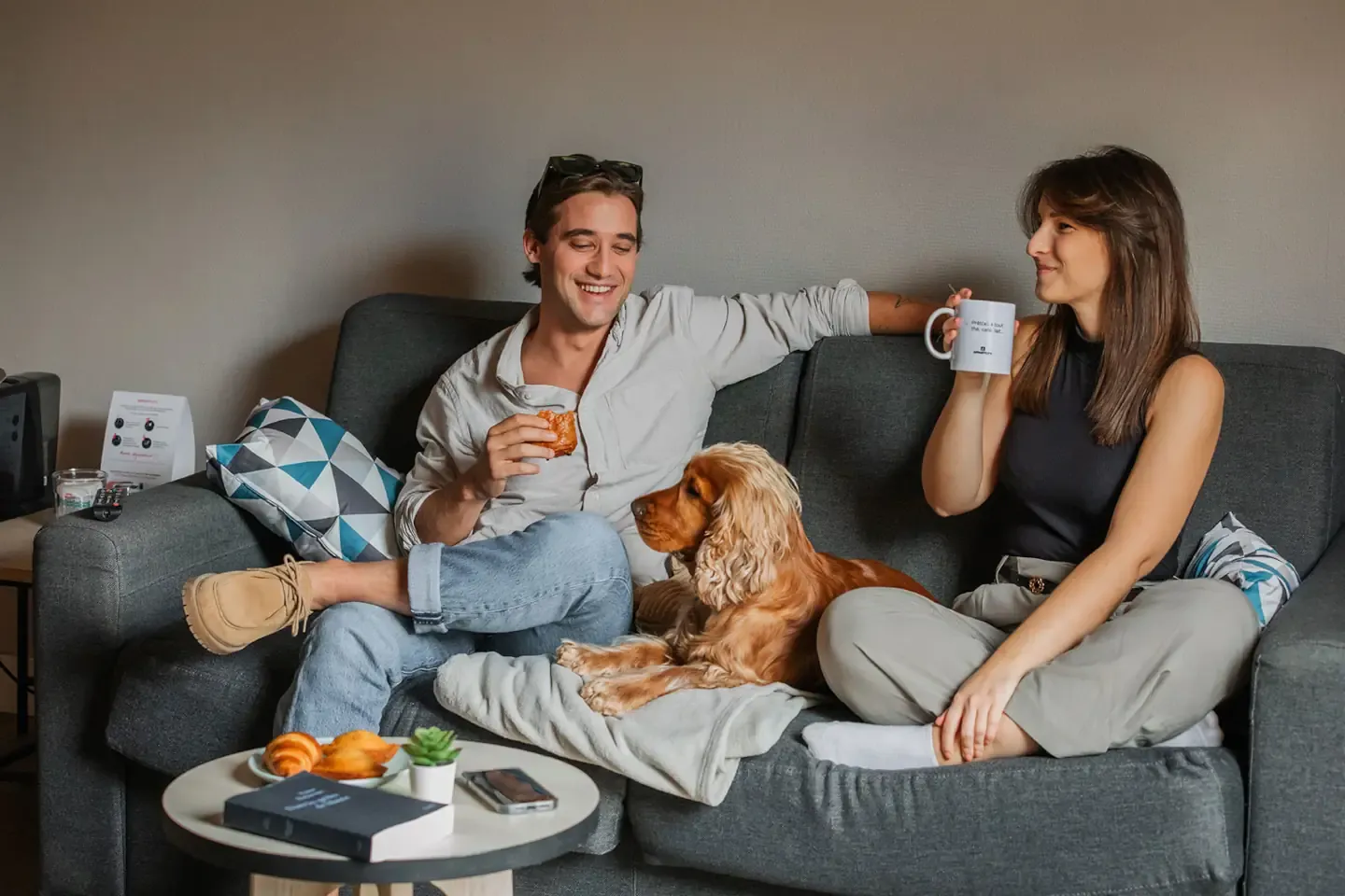 Paar sitzt mit einem Hund auf einem Sofa im Wohnzimmer