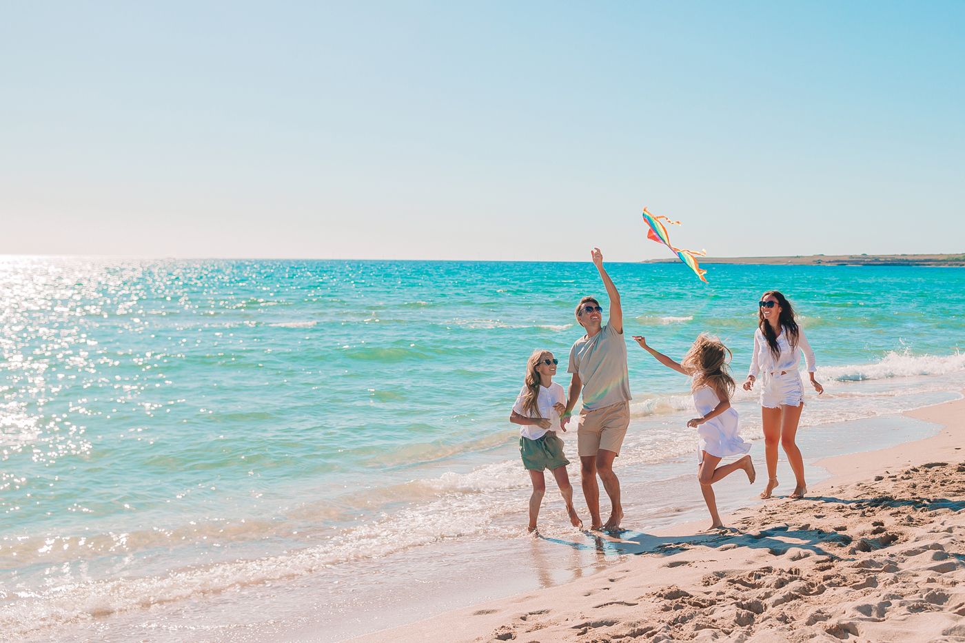 Familie geht am sonnigen Strand pres de la mer bleues e