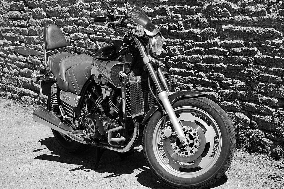 Vintage black motorcycle displayed against an ancient stone wall, perfect for two-wheel enthusiasts. Stay in the comfort of an Appart'City during the Salon du 2 Roues in Lyon for a complete experience.