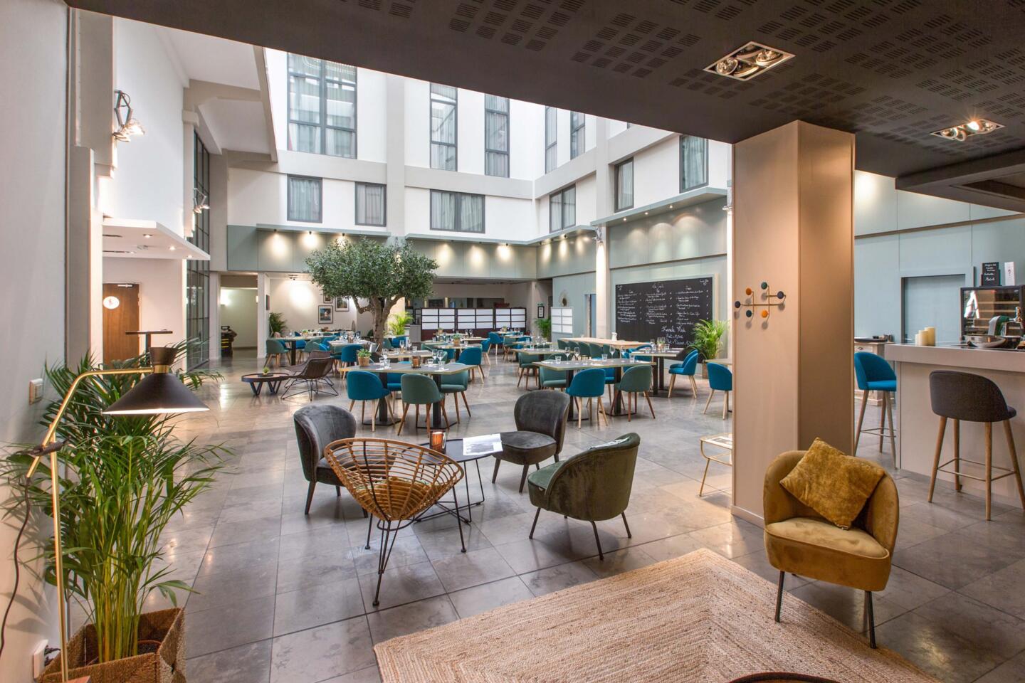 Restaurant Bistrot City d'Appart’City Lyon Cité Internationale avec verrière lumineuse, mobilier design bleu et vert, grands espaces ouverts et ambiance moderne et conviviale