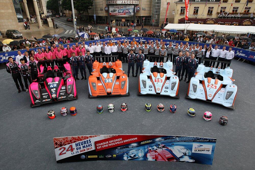 Equipo de carreras y sus coches preparados para las 24 Horas de Le Mans, mostrando colores y números distintivos del equipo para el evento de carrera de resistencia.