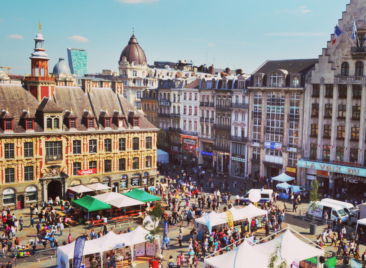 Place animée pendant la Braderie de Lille, foisonnante de stands de marché et de foule, avec des bâtiments historiques en arrière-plan, à proximité des appart'hôtels Appart'City.