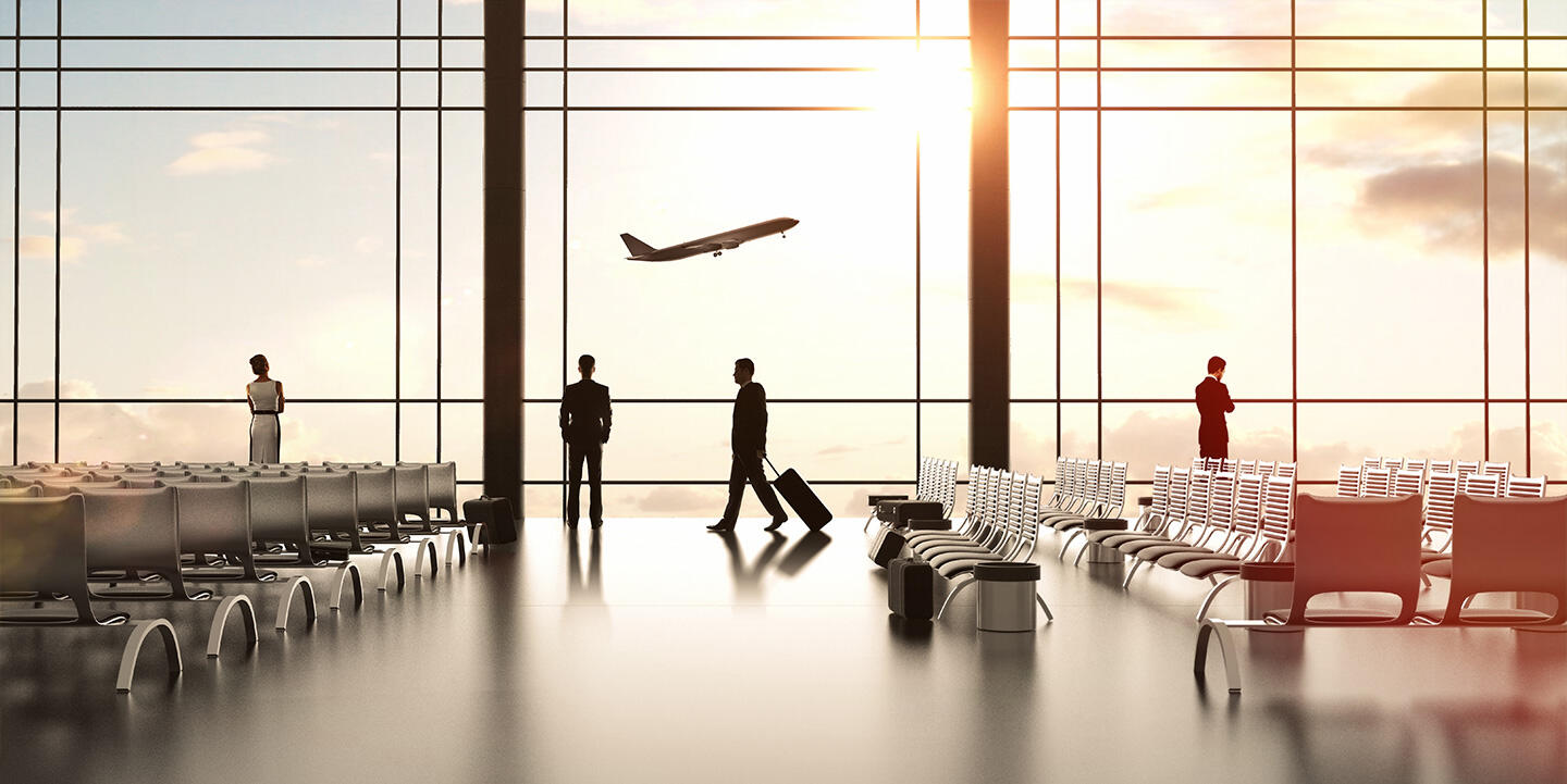 The bright interior of the airport concourse with passengers walking and contemplating the view of a plane taking off at sunset through huge picture windows, evoking easy access to apartment-hotel-style accommodation.