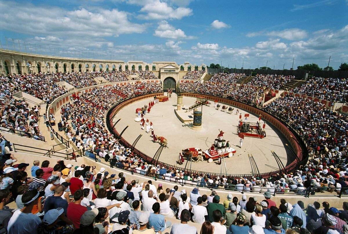 Zuschauer sitzen auf den Rängen des gallo-römischen Stadions von Puy du Fou und genießen eine historische Nachstellung, während sie ihren Aufenthalt in La Roche-sur-Yon voll auskosten.