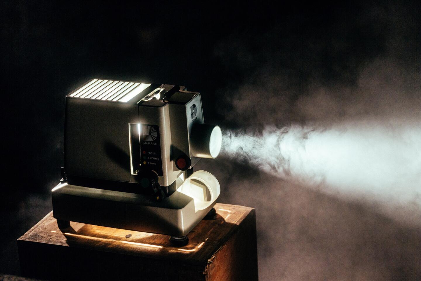 Vintage film projector casting a beam of light through atmospheric smoke, capturing the nostalgic ambiance at the Angoulême Francophone Film Festival.