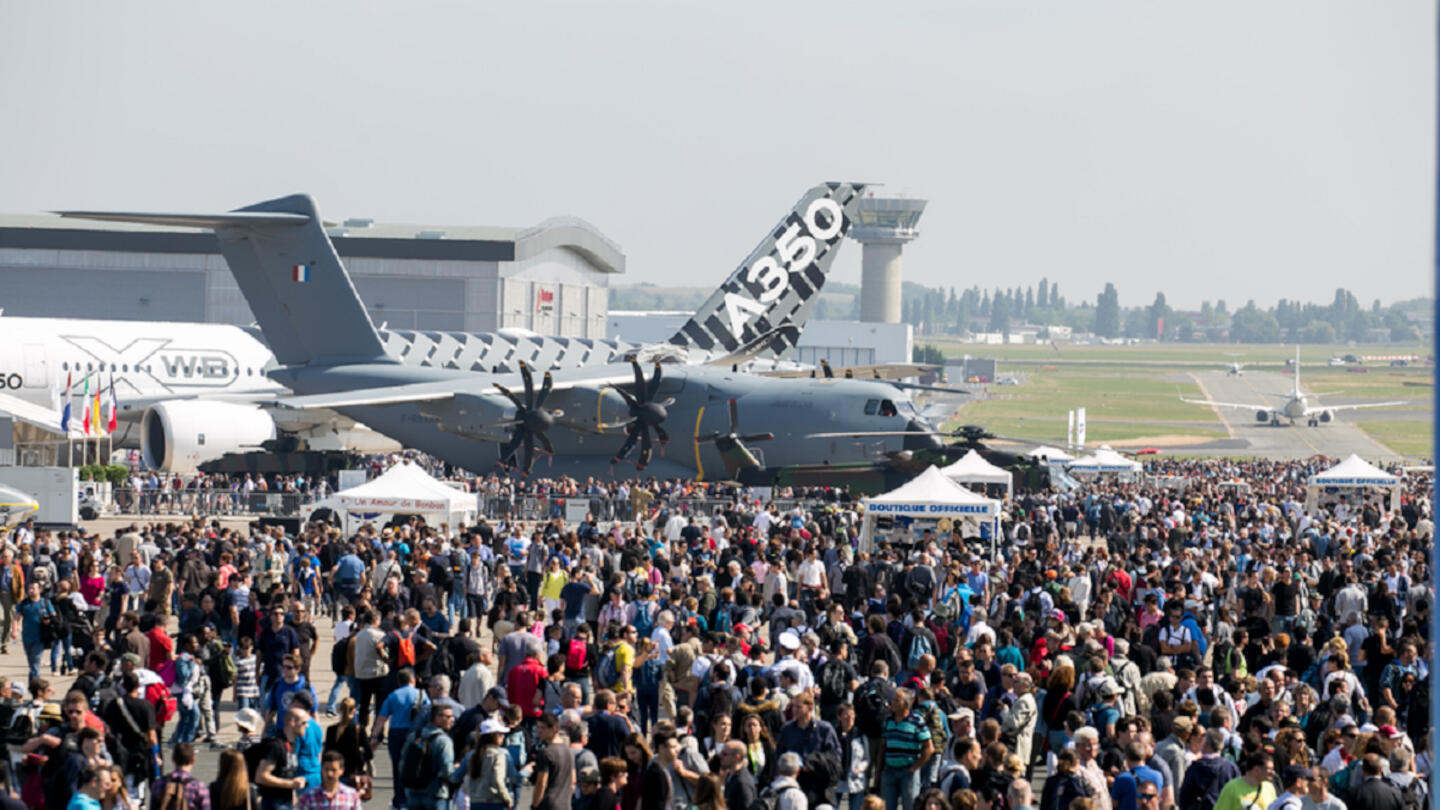 Large crowd at the International Paris Air Show with an A380 aircraft in the background