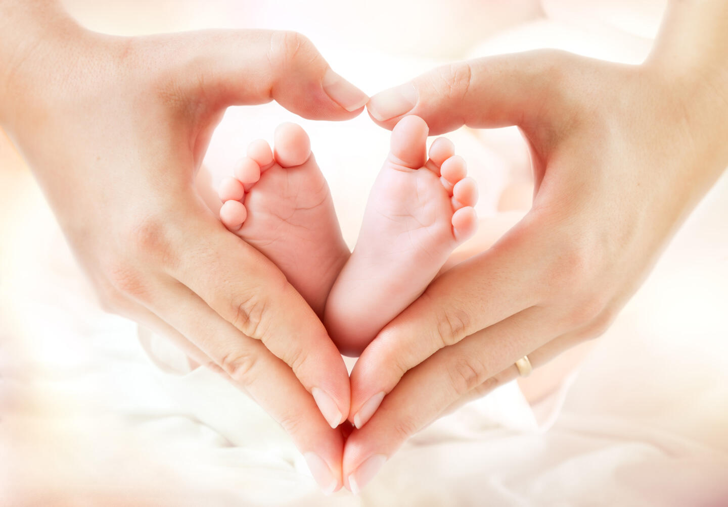 Hands forming a heart around a baby's feet, symbolizing parental love and care at the Baby and Me fair in Geneva.
