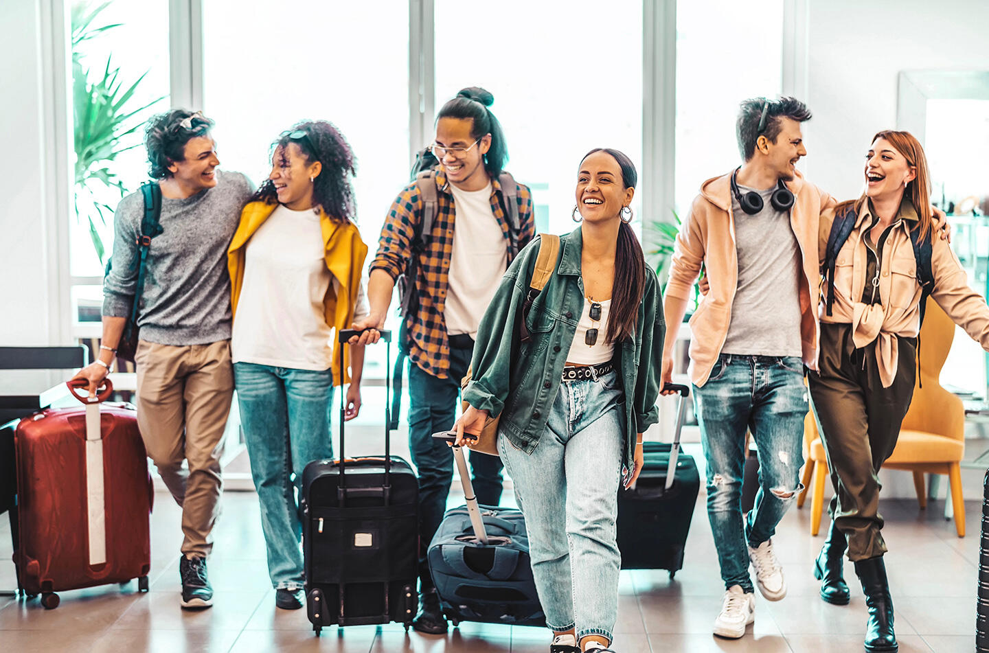 Fröhliche Gruppe von Freunden mit Gepäck am Flughafen Toulouse-Blagnac, Beginn einer aufregenden Reise.