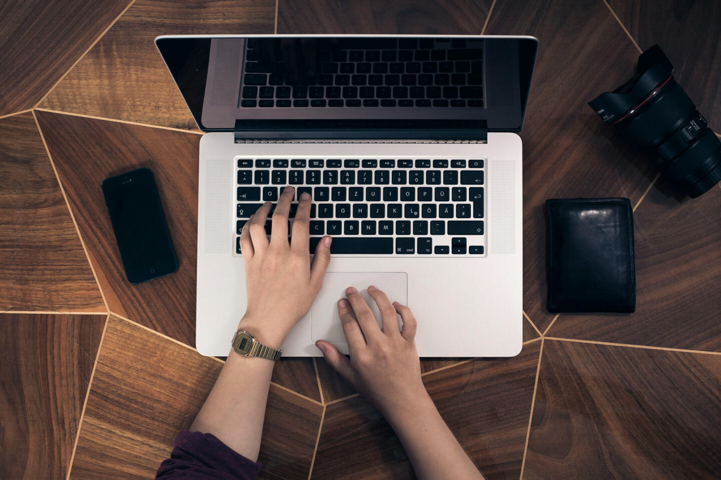 User working on data privacy on a laptop, surrounded by a mobile phone and a camera, symbolizing secure personal information management.