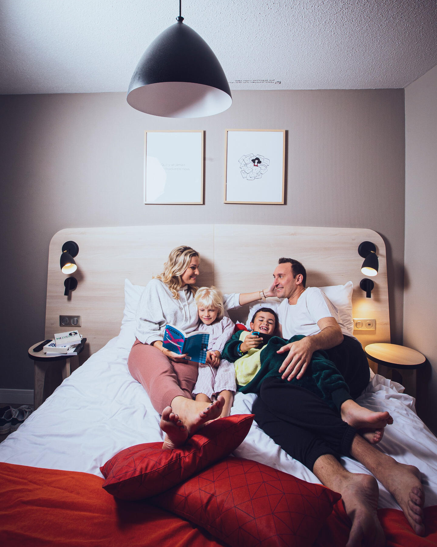 Smiling family enjoying a reading moment together in a comfortable Appart'City aparthotel.