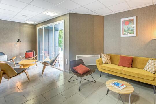 Salón moderno y acogedor con sofá amarillo, sillones de diseño e iluminación suave, para relajarse en una residencia urbana.