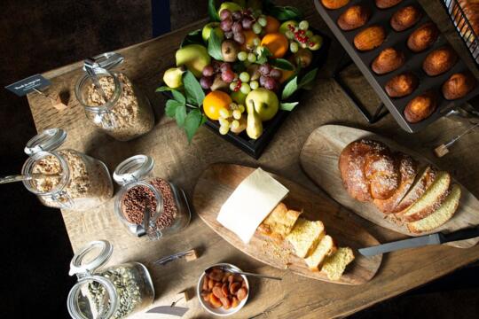 Petit déjeuner gourmet dans un appart'hôtel de la gamme Collection, avec fruits frais, pain artisanal, pâtisseries, céréales et fruits secs.
