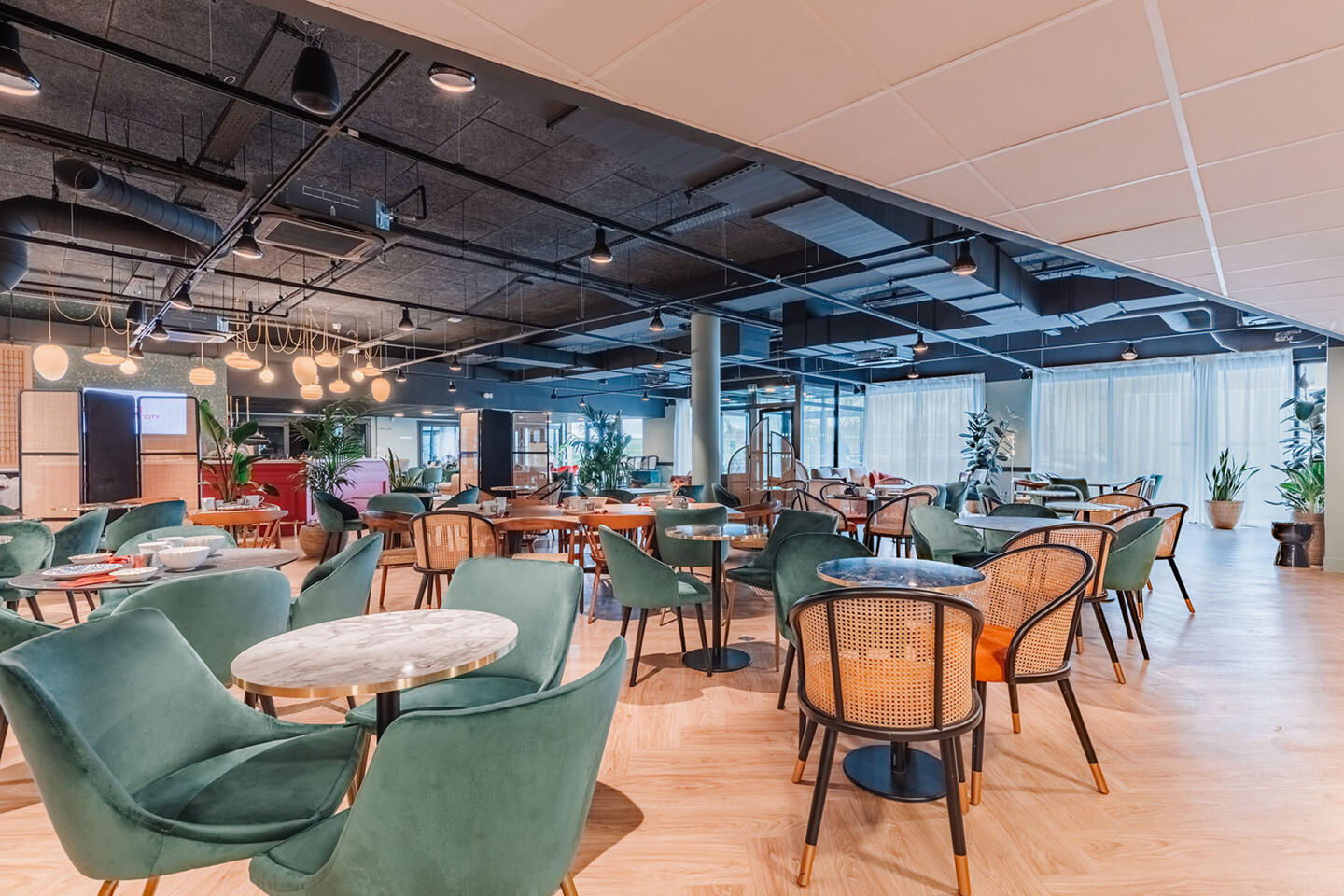 Restaurant moderne et spacieux à Appart'City, avec des fauteuils verts, des tables en marbre et une décoration élégante dans des tons naturels.