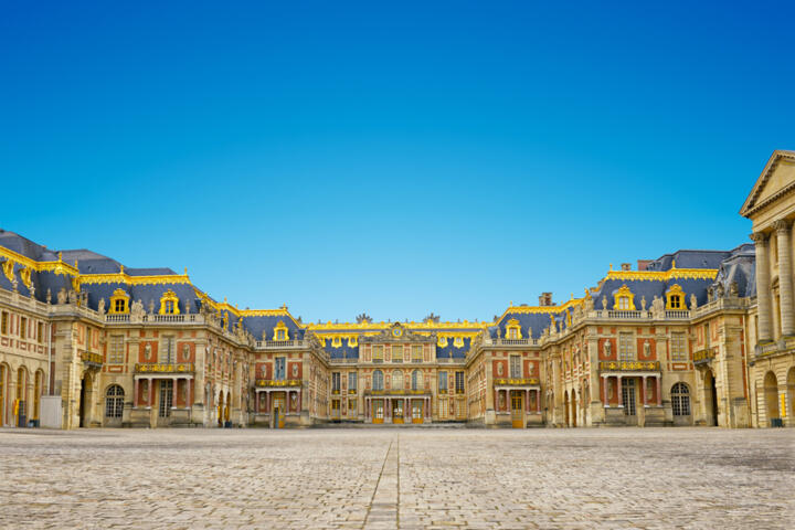 Façade principale du château de Versailles sous un ciel bleu, symbole du patrimoine royal français