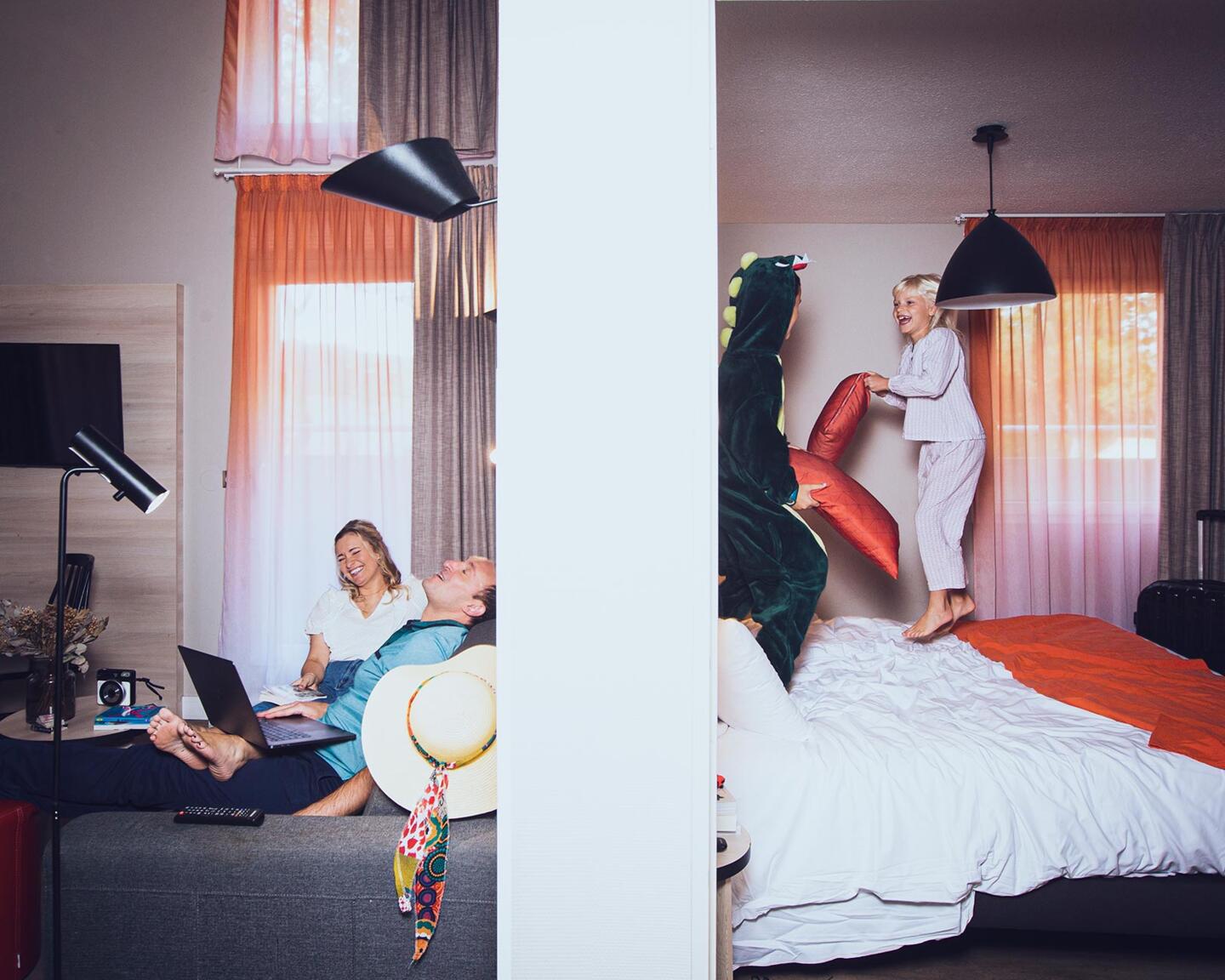 Family in an aparthotel stay: parents relaxing, kids playing on the bed