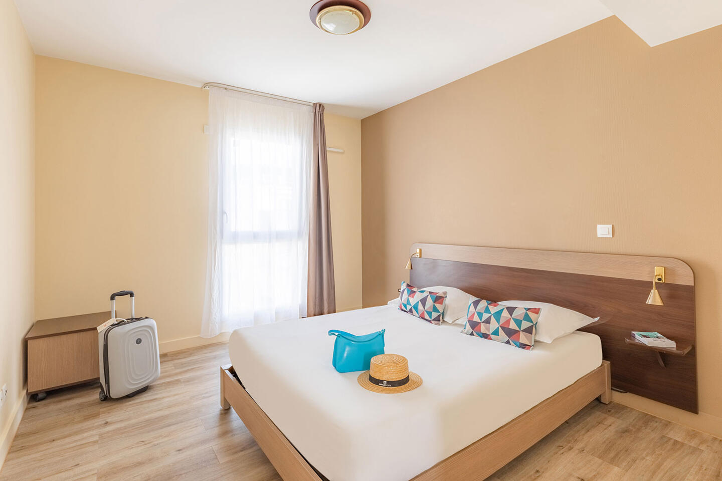 Helles und modernes Zimmer in einem Appart'City-Aparthotel in Nizza mit Doppelbett, Koffer und Reiseaccessoires